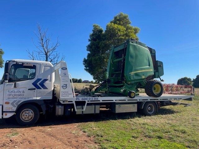 A Truck Is Parked With A Tractor On The Back Of It — Torquay & Anglesea Accident Towing Centre In Torquay, VIC