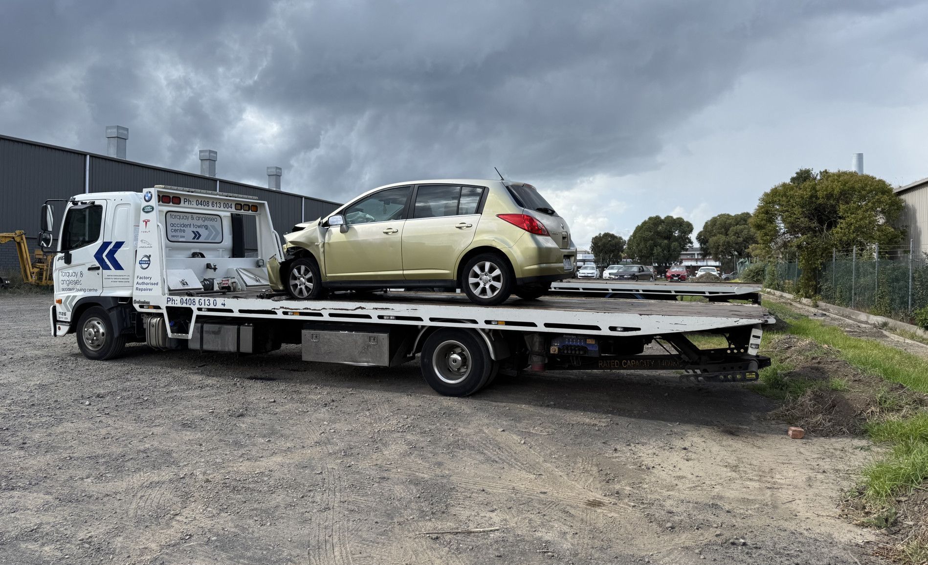 A Tow Truck Is Towing A Broken Down Car On A City Street — Torquay & Anglesea Accident Towing Centre In Torquay, VIC