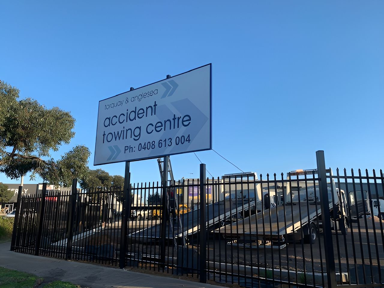A Sign For Accident Towing Centre Hangs Above A Fence — Torquay & Anglesea Accident Towing Centre In Torquay, VIC