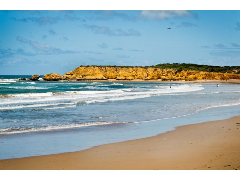 A Beach With Waves And A Cliff In The Background — Torquay & Anglesea Accident Towing Centre In Torquay, VIC