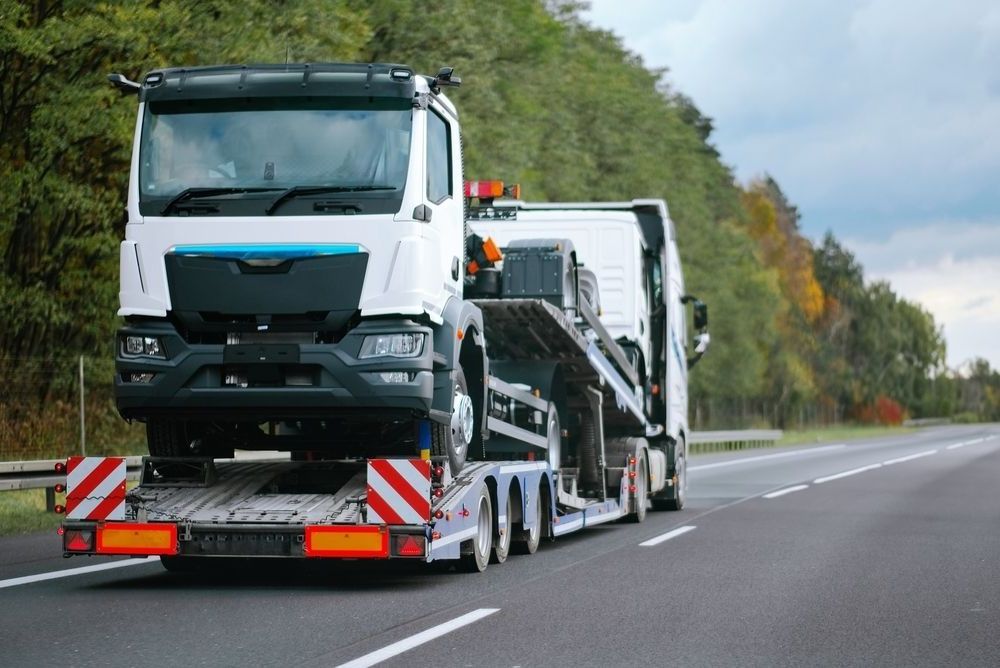 A Truck Is Driving Down A Highway With A Car — Torquay & Anglesea Accident Towing Centre In Bacchus Marsh, VIC