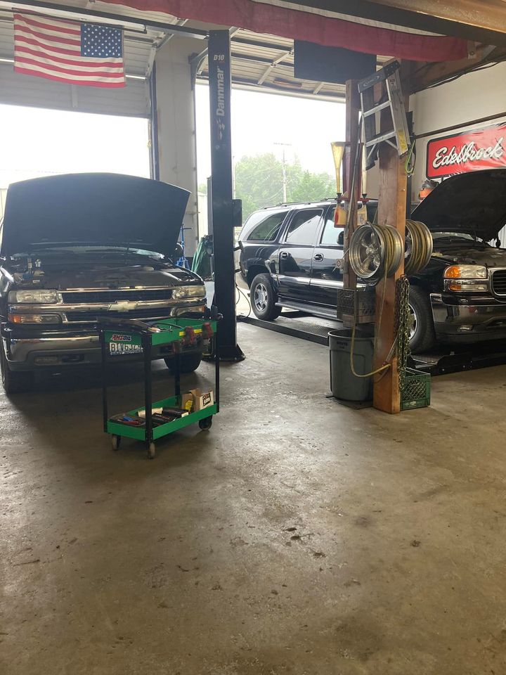 A truck is sitting on a lift in a garage with the hood up.