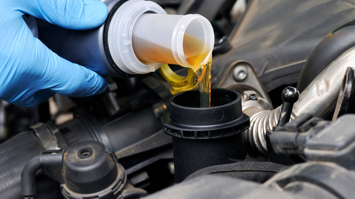 A person is pouring oil into a car engine.