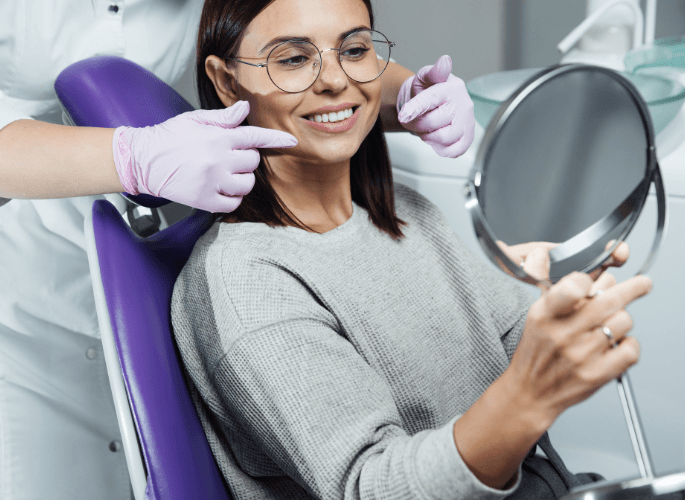 woman at dentist smiling in mirror | Best restorative dentist in Escondido CA 92026