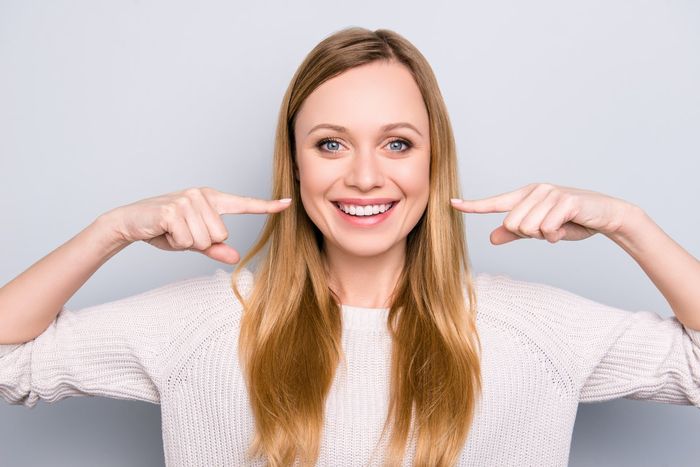 woman smiling pointing to smile | Cosmetic dentistry | Veneers, Invisalign, Teeth whitening | Escondido CA 