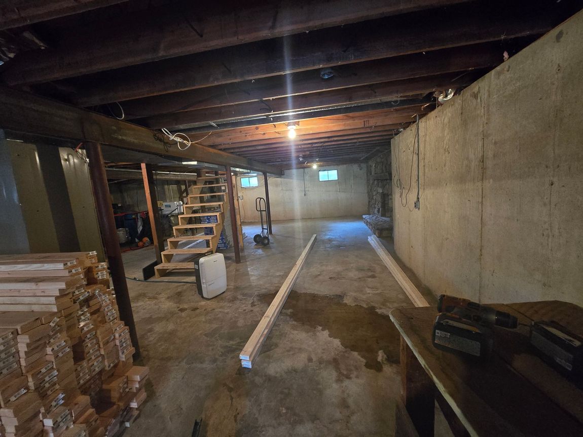 A basement with a wooden ceiling and stairs.