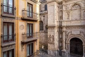 A view of a building with balconies and a church in the background.