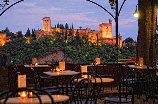 A view of a castle from a restaurant with tables and chairs
