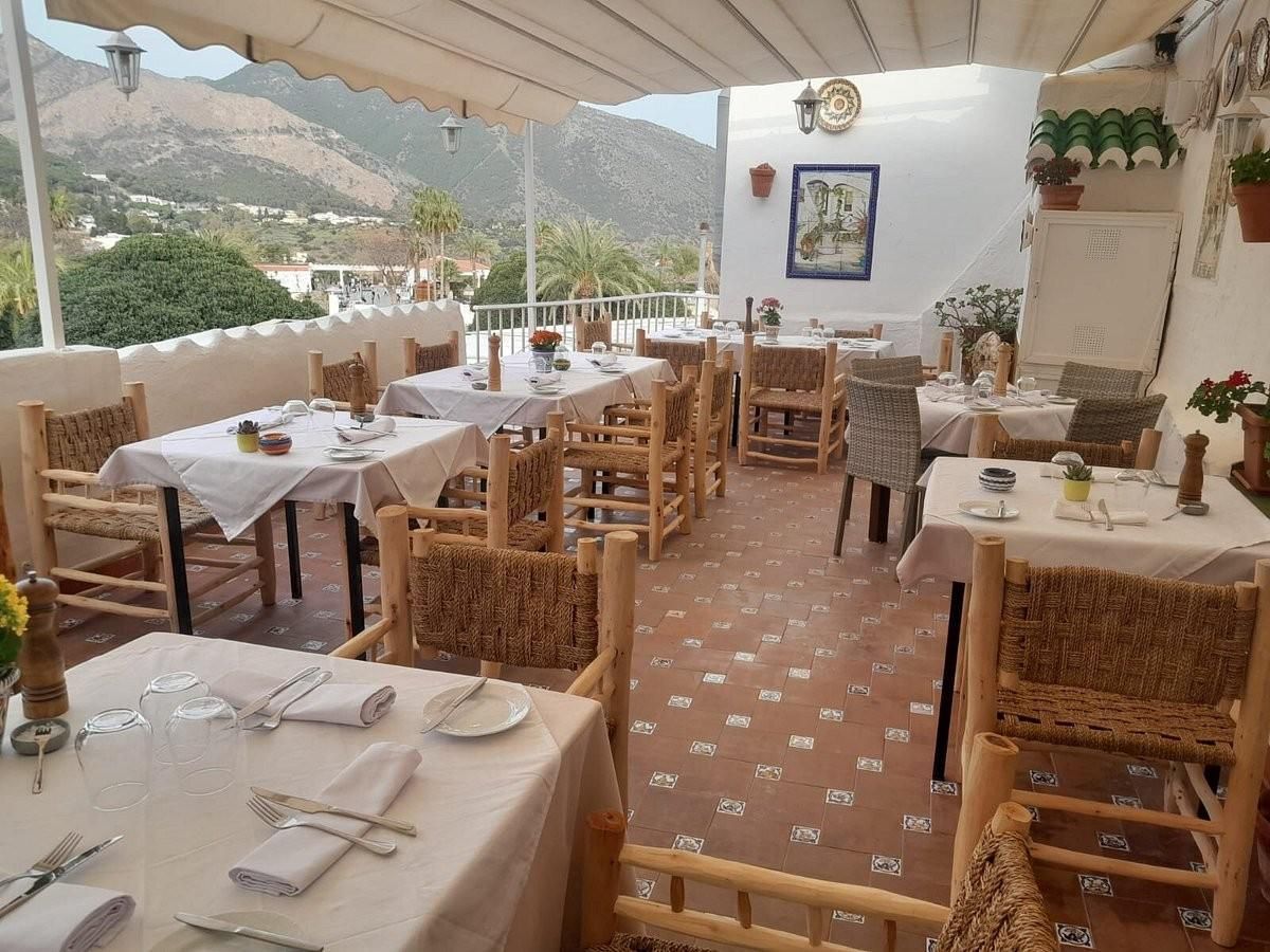 A restaurant with tables and chairs and a view of the mountains