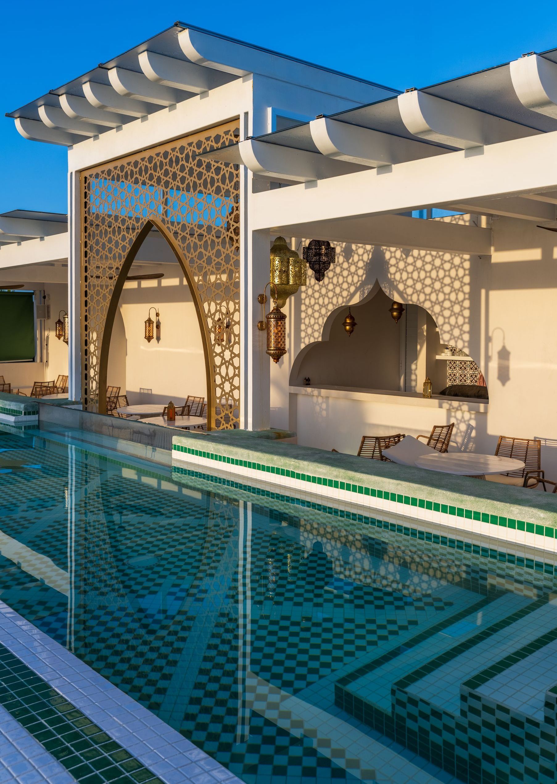 Pool area with decorative archway and lanterns; light blue water reflects the architecture.