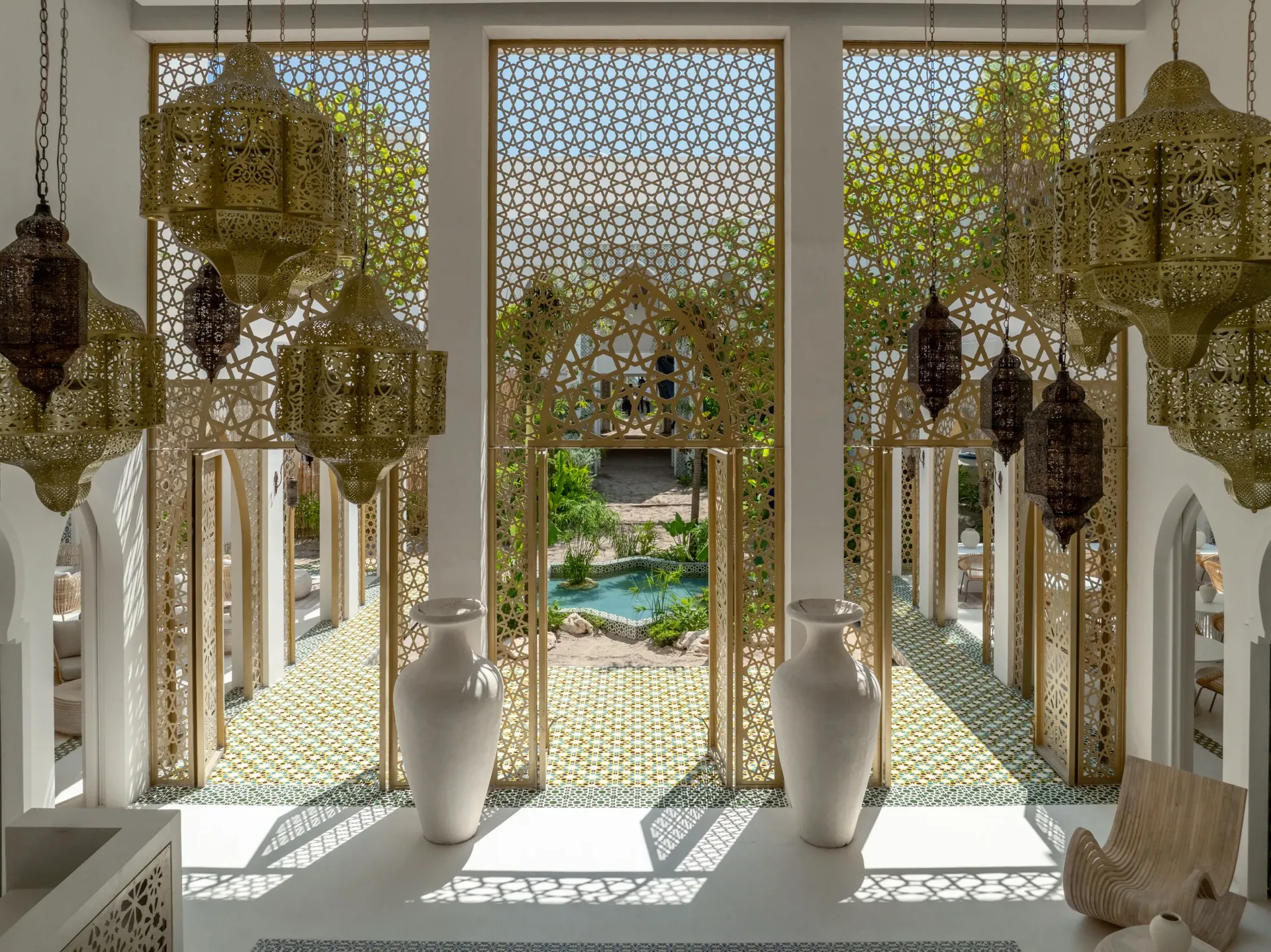 Ornate room with golden lanterns, decorative screens, and view of a courtyard with water feature.