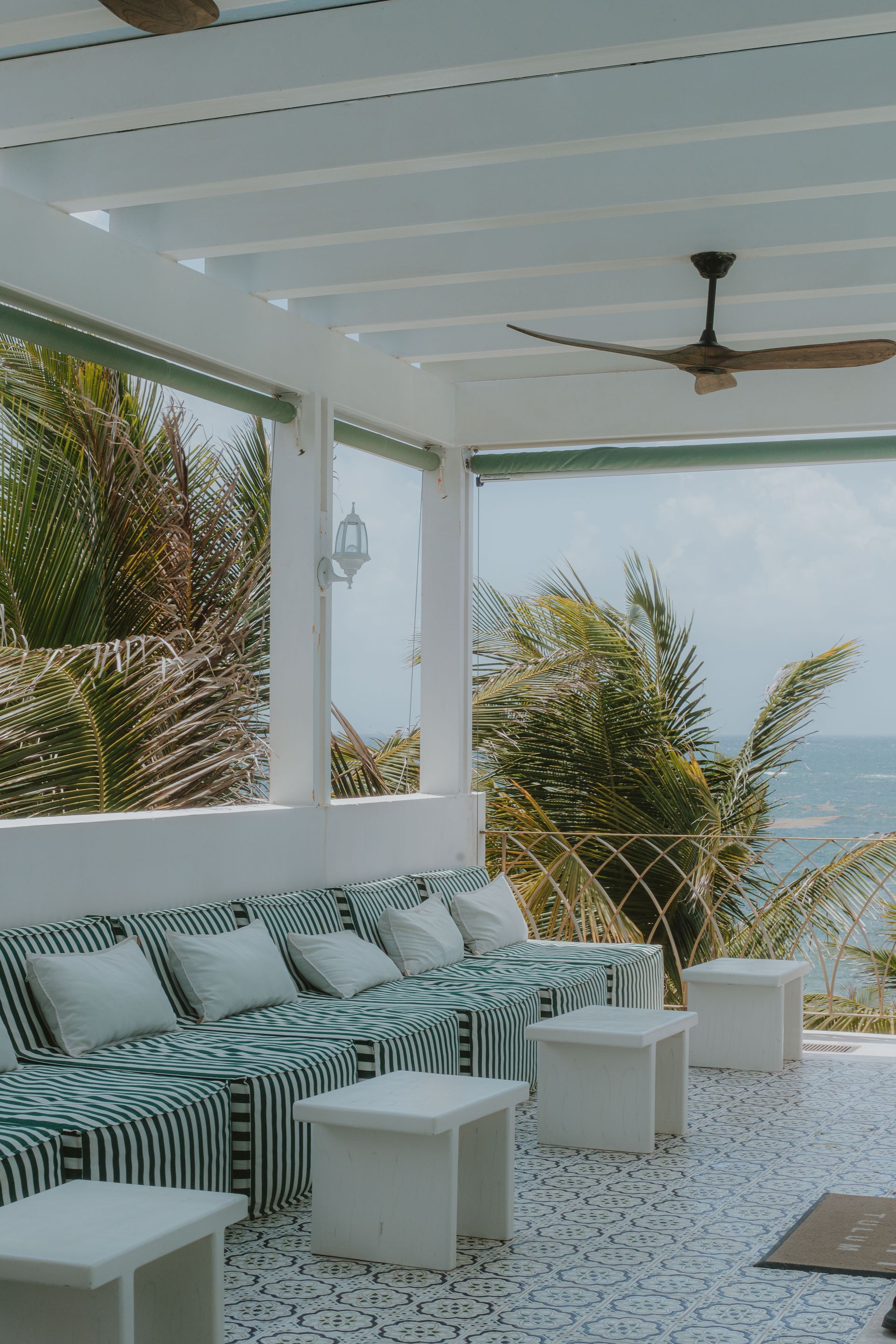 Outdoor seating area with striped cushions, white tables, and ocean view.
