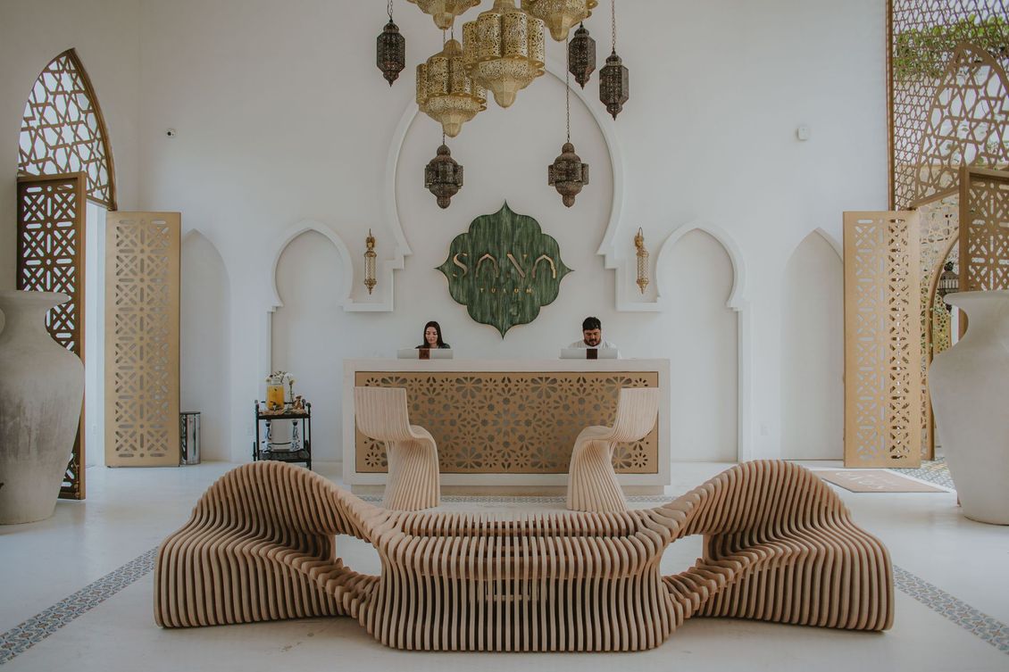 Bright white lobby with ornate decor, reception desk, and unique wooden seating.