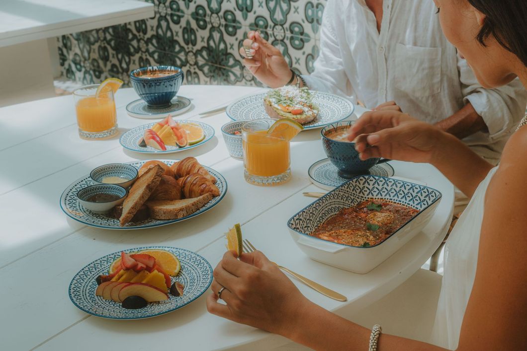 People at a table enjoying breakfast: croissants, fruit, juice, and coffee.