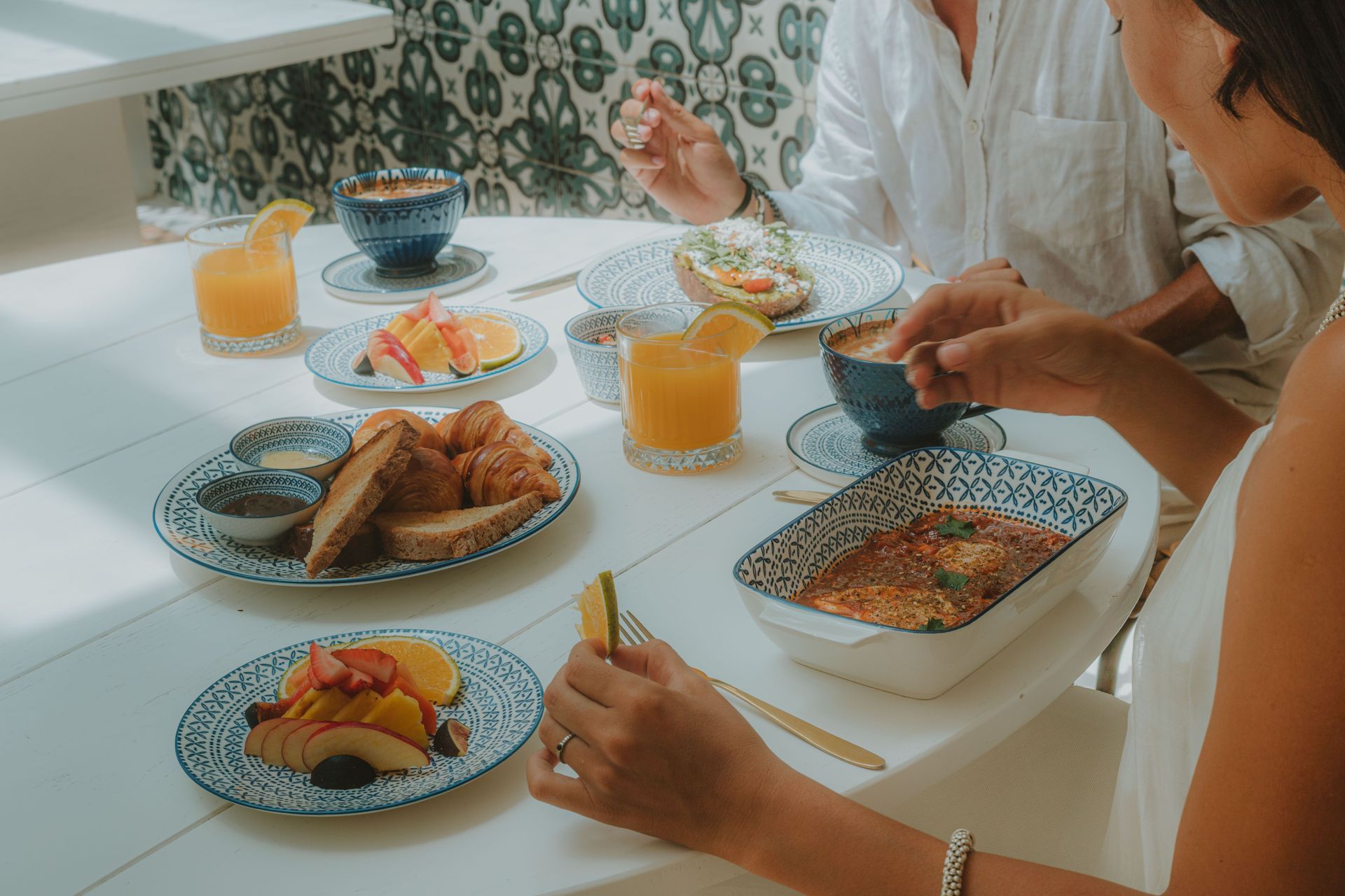 People at a table enjoying breakfast: croissants, fruit, juice, and coffee.