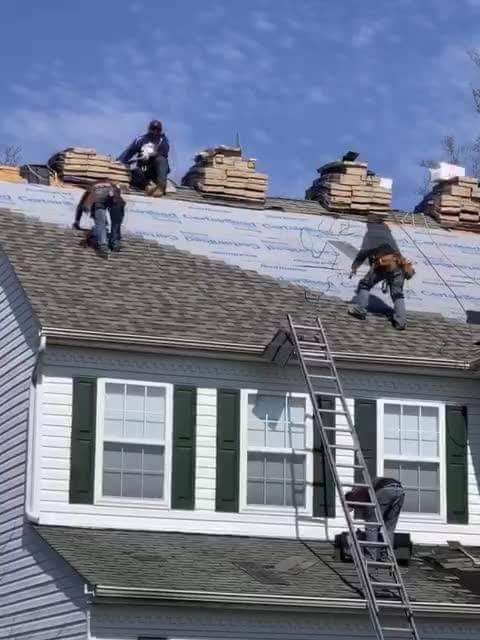 A group of men are working on the roof of a house.