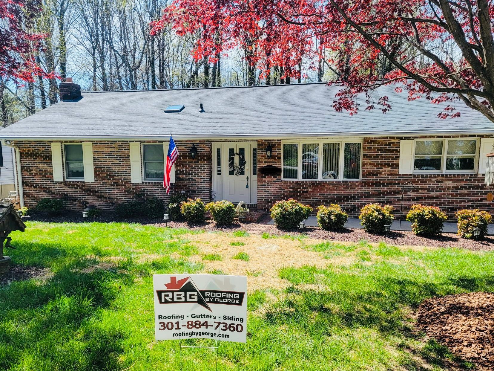 A house with a sign in front of it that says rbg roofing.