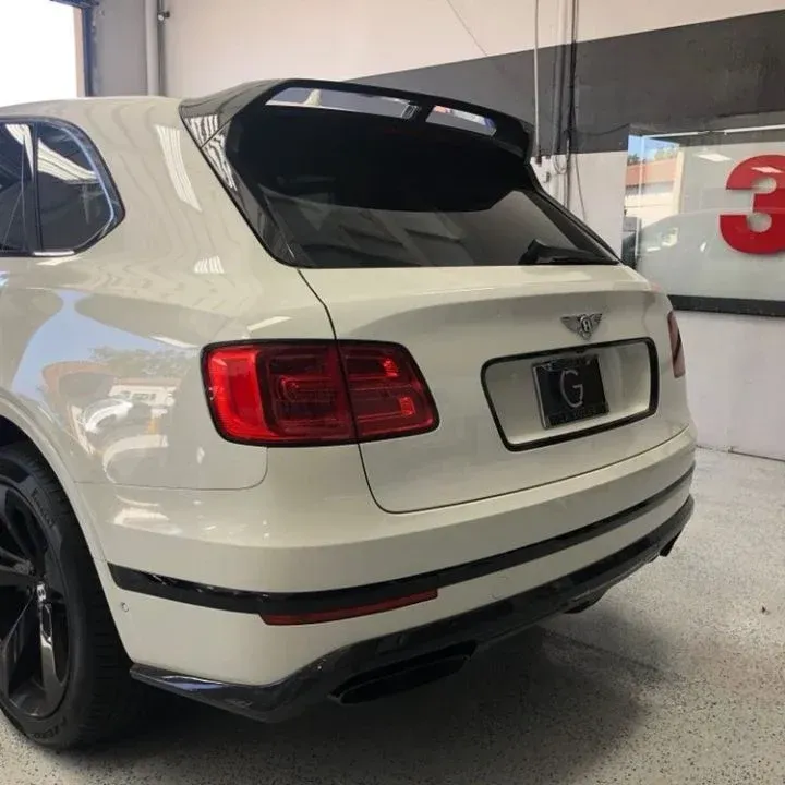 White Bentley SUV with black accents, parked in a garage.