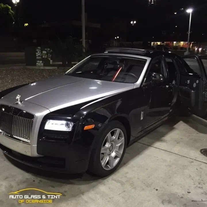 Black and silver Rolls Royce parked at night with door open.