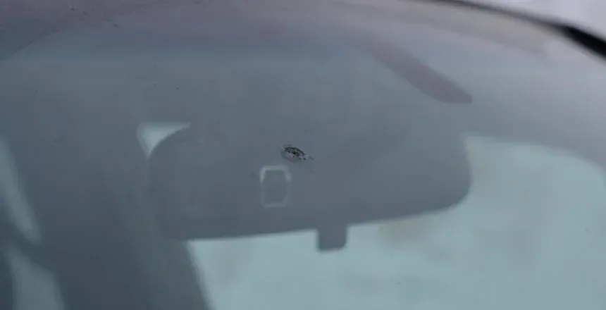 Windshield with a chip, rearview mirror visible.
