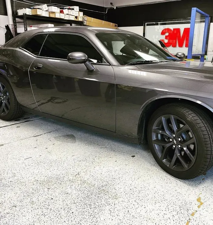 Gray Dodge Challenger with tinted windows parked in a garage.