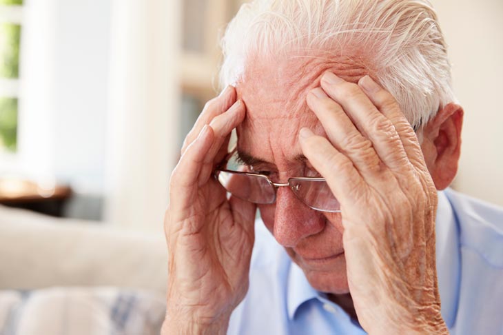 elderly man with hands on head seeming frustrated