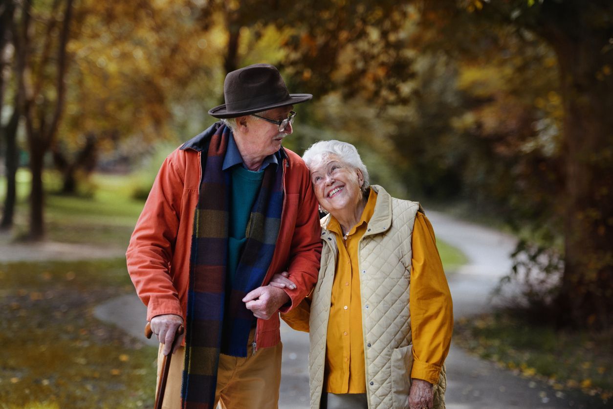 an elderly couple out for a nature walk looking lovingly at each other