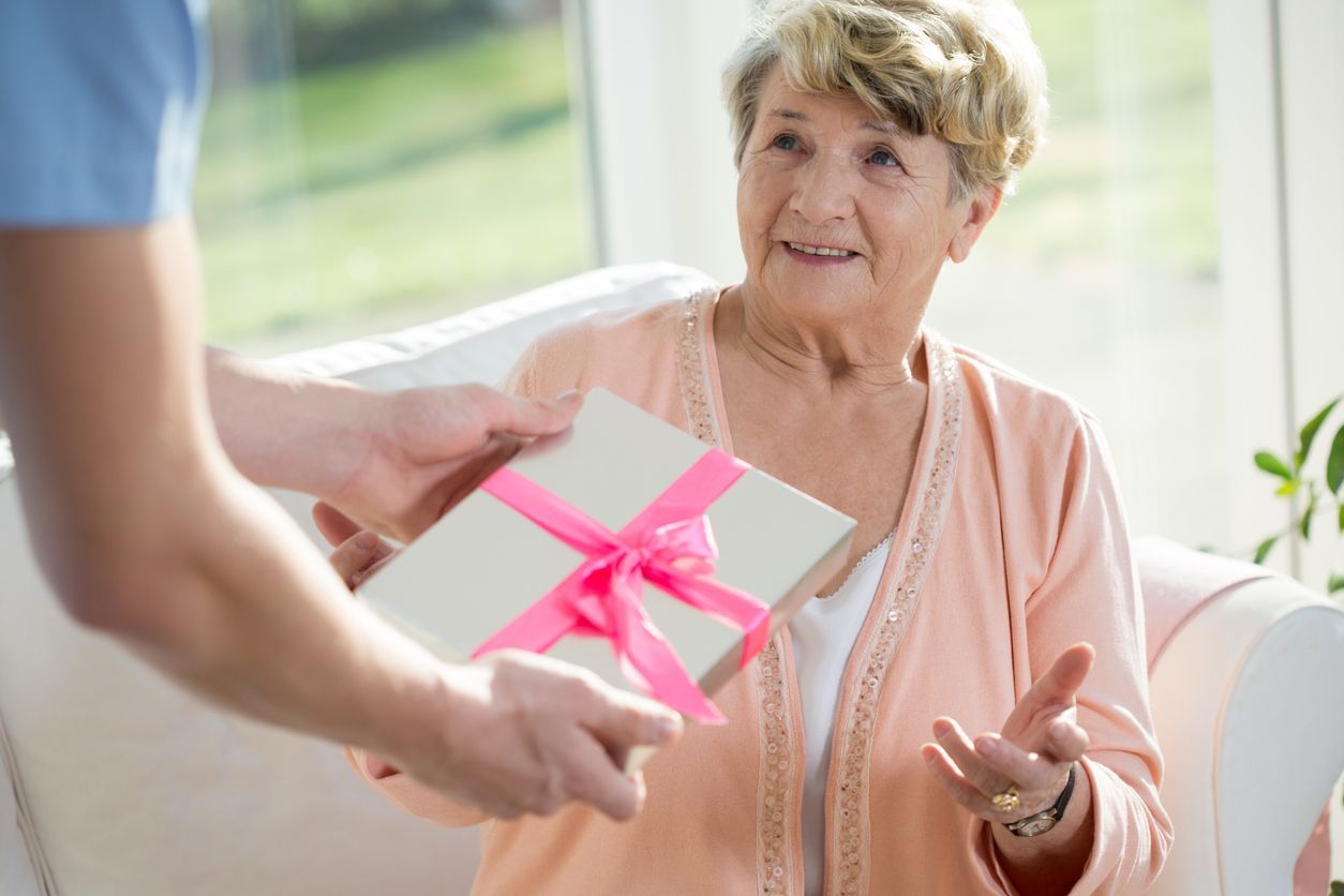 Male nurse giving a present to an elderly woman at a nursing home.