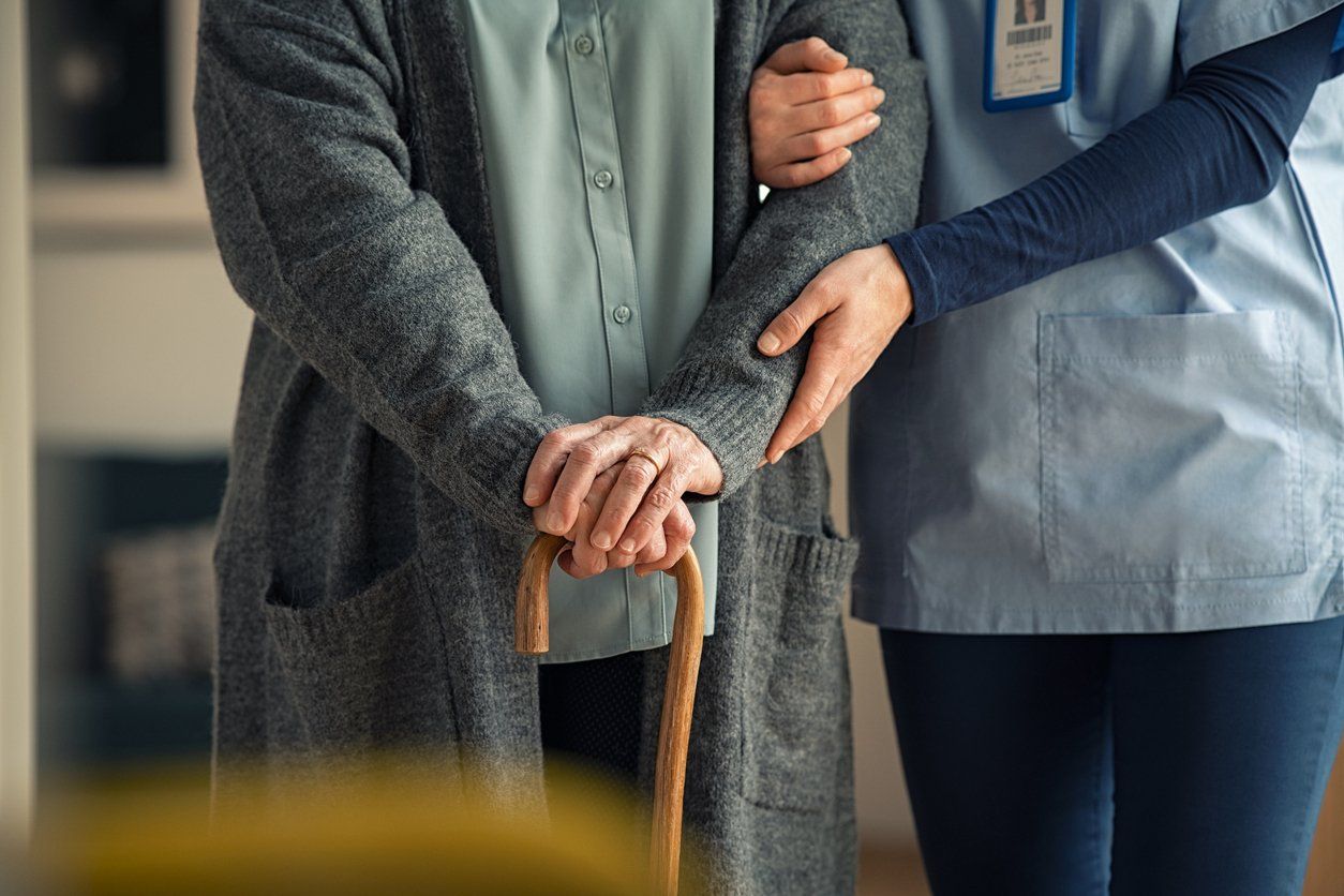 detail shot of a caregiver helping an elderly patient walk