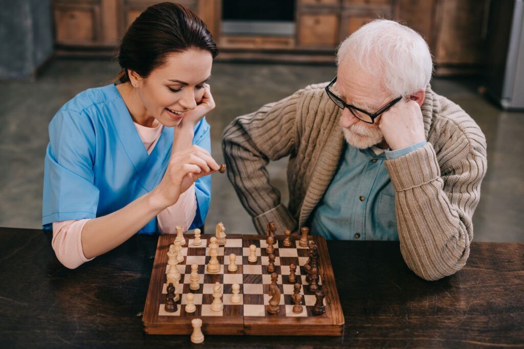 caregiver playing chess with elderly man
