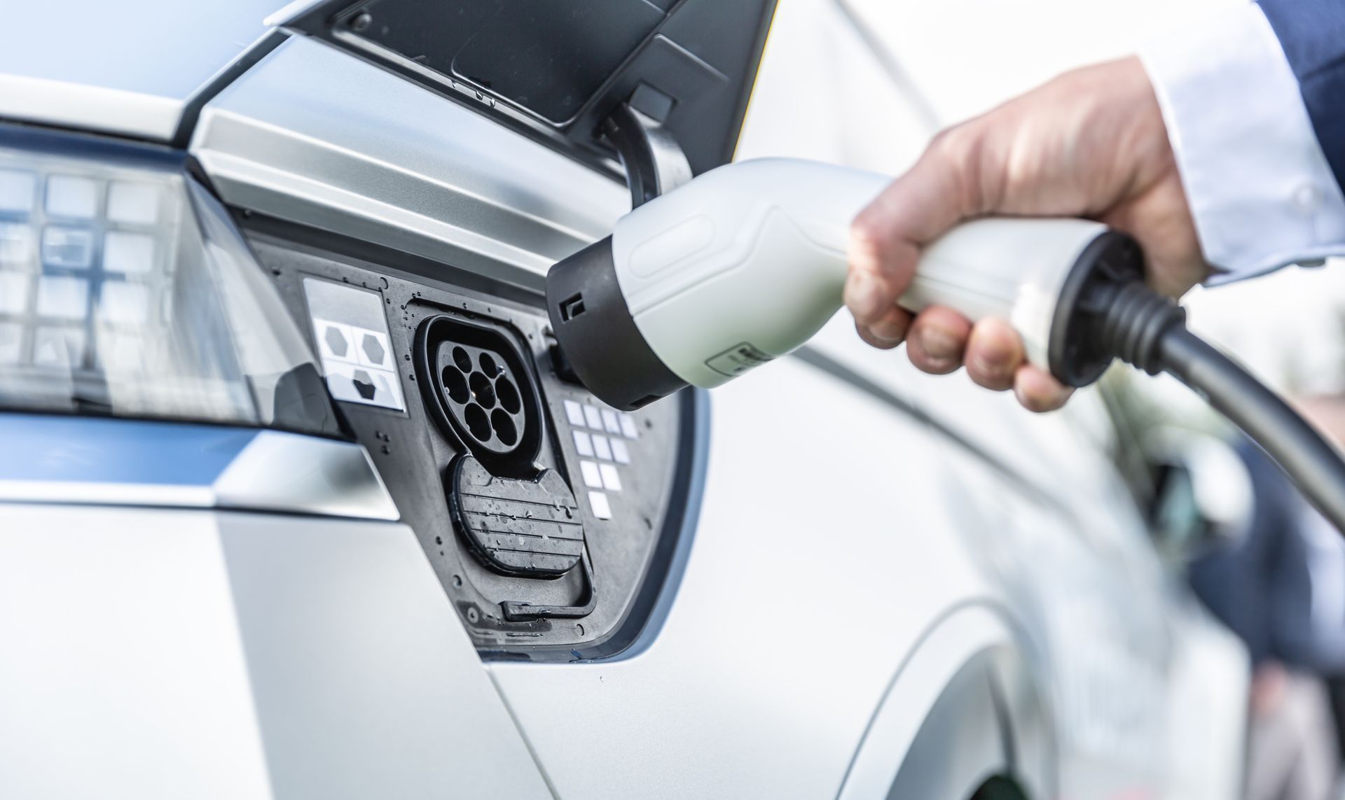 Person plugging an electric vehicle charger into a car's charging port.