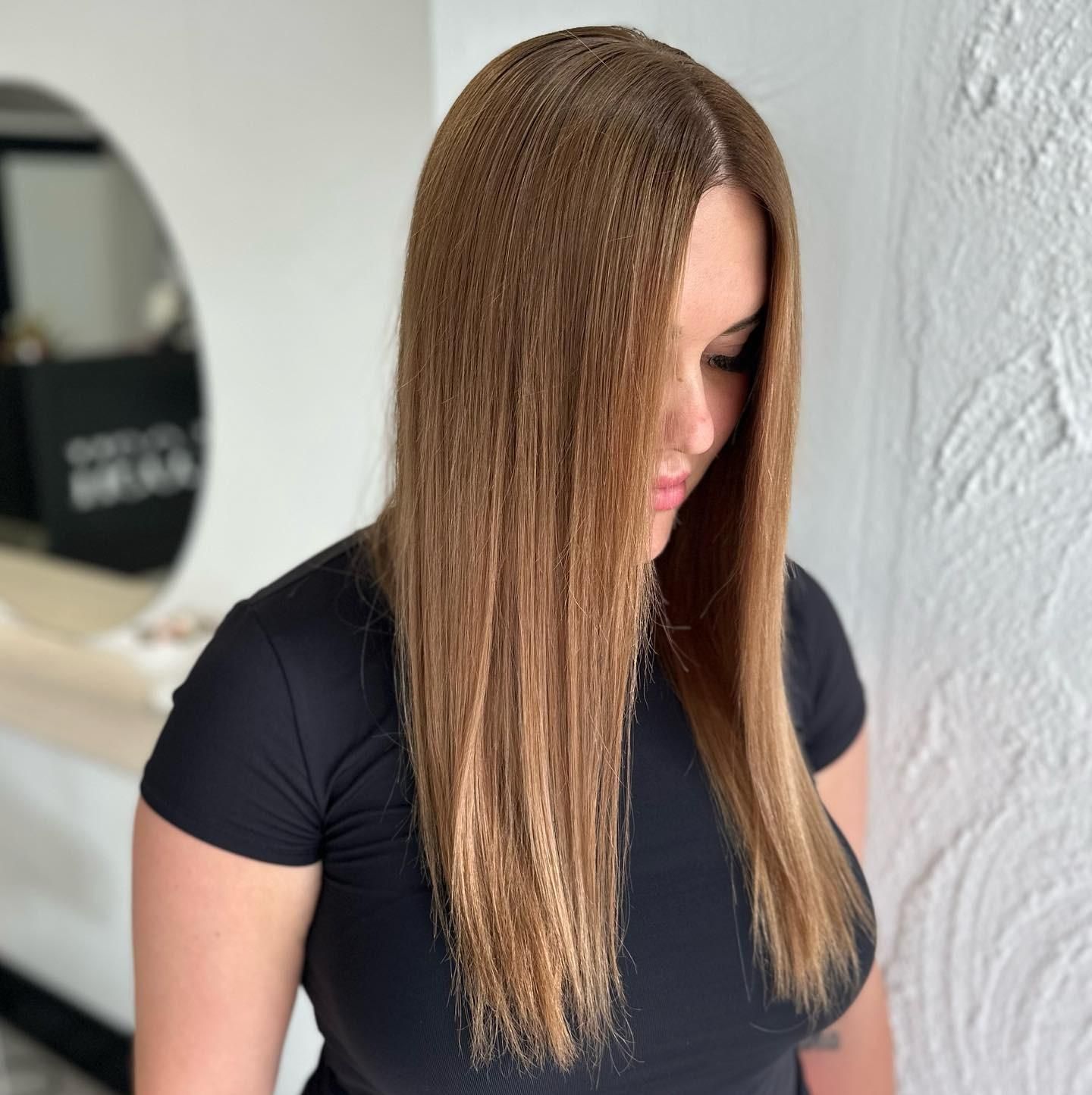 A Woman with Long Brown Hair Is Wearing a Black Shirt — Losh Hair Lounge In Toowoomba City, QLD