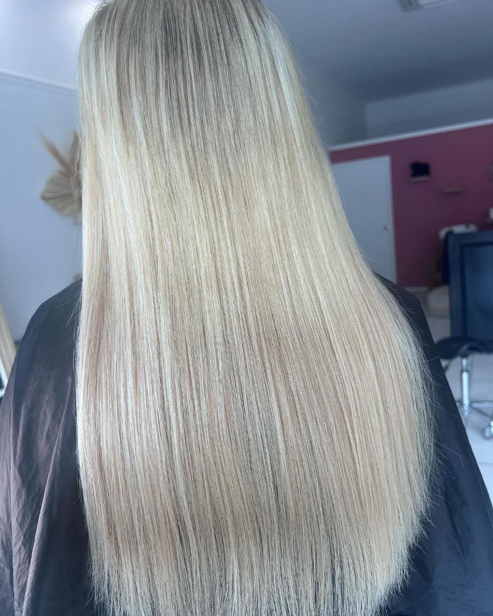 A Woman with Long Blonde Hair Is Wearing a Black Cape — Losh Hair Lounge In Toowoomba City, QLD