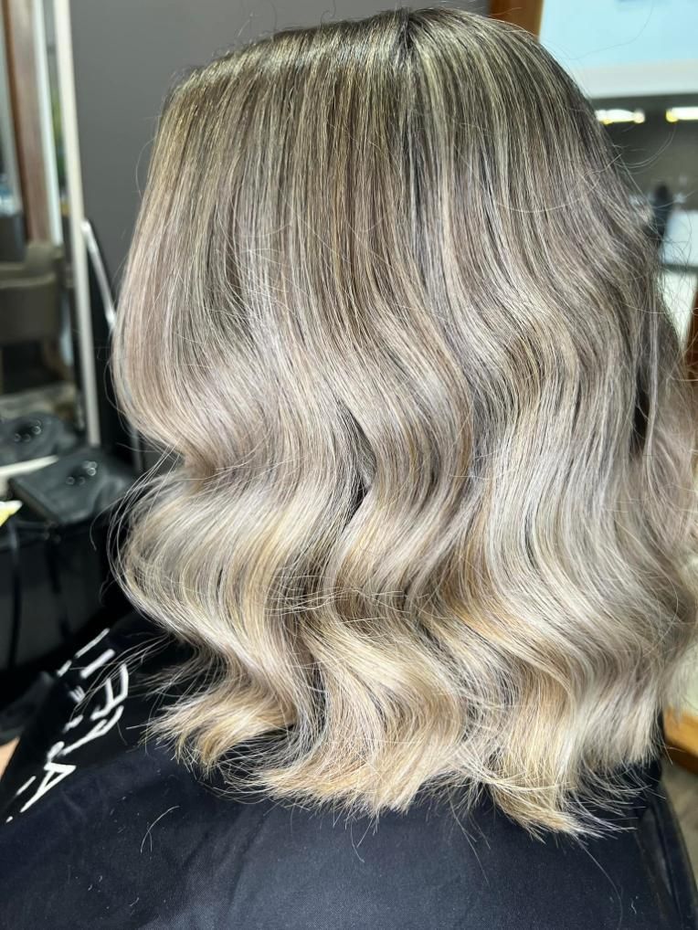 A Woman with Blonde Wavy Hair Is Sitting in A Chair in A Salon — Losh Hair Lounge In Toowoomba City, QLD