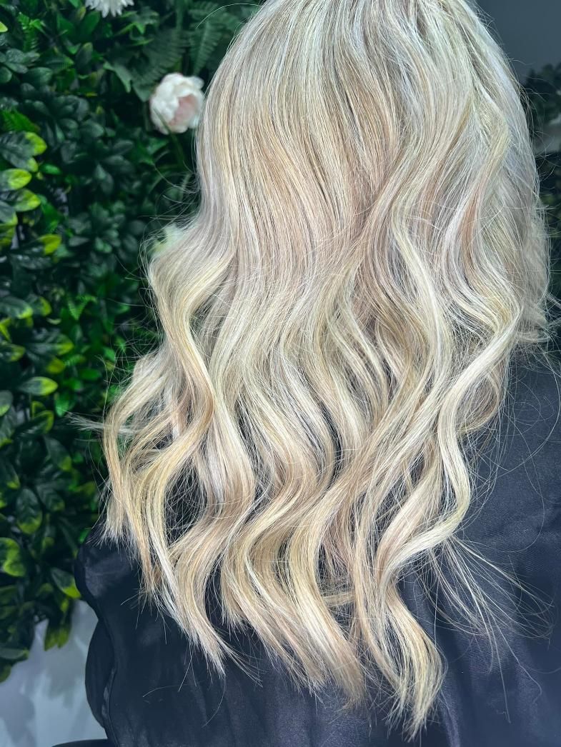 A Woman with Blonde Hair Is Sitting in Front of A Bush — Losh Hair Lounge In Toowoomba City, QLD