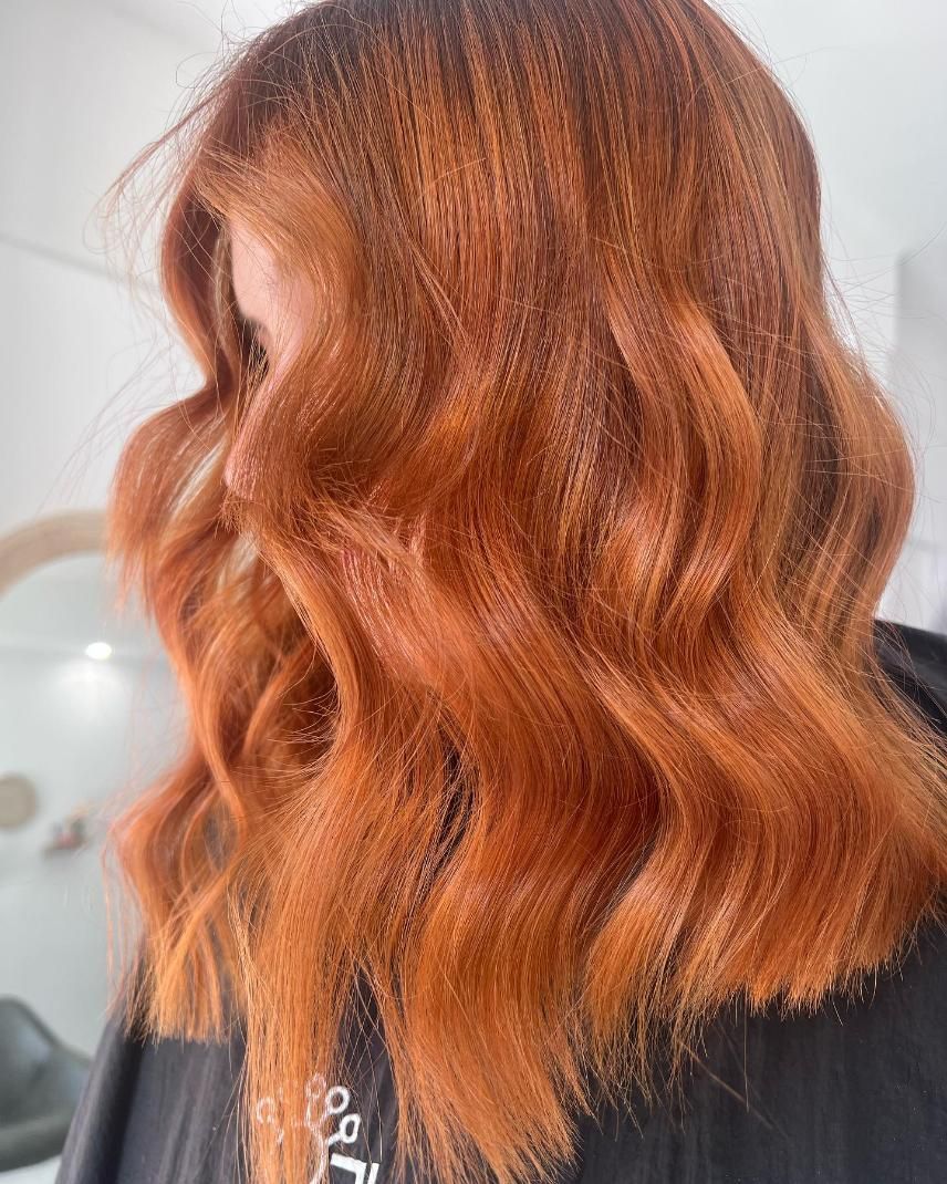 A Woman with Long Red Hair Is Standing in Front of A Mirror — Losh Hair Lounge In Toowoomba City, QLD