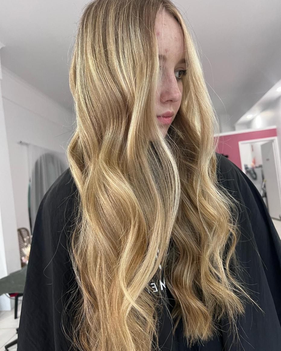 A Woman with Long Blonde Hair Is Wearing a Black Cape — Losh Hair Lounge In Toowoomba City, QLD