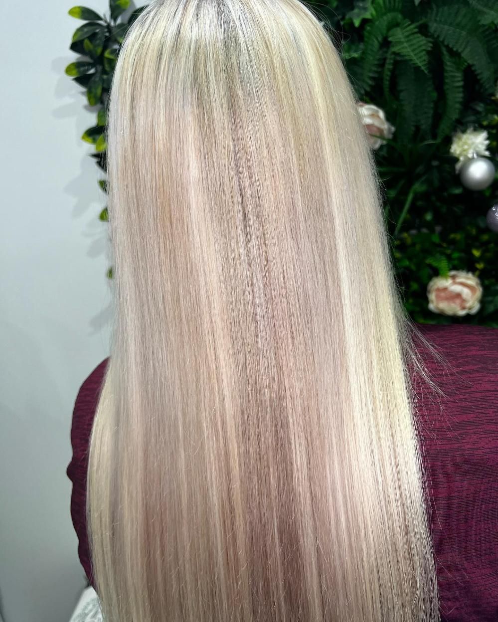 A Woman with Long Blonde Hair Is Sitting in Front of A Christmas Tree — Losh Hair Lounge In Toowoomba City, QLD