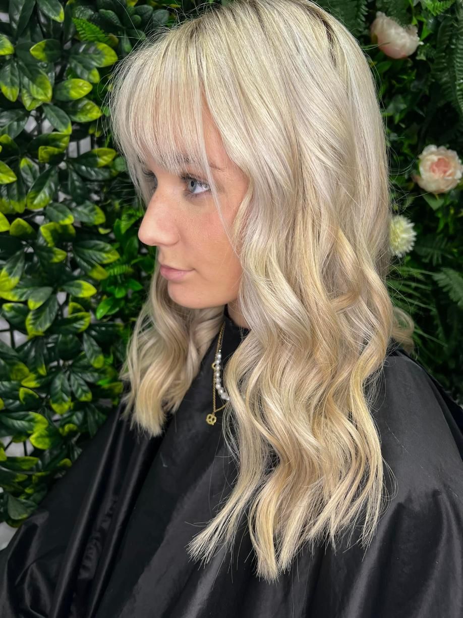 A Woman with Blonde Hair Is Wearing a Black Cape — Losh Hair Lounge In Toowoomba City, QLD