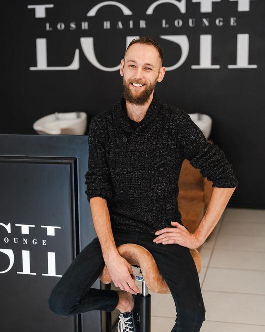 A Man Is Sitting on A Stool in Front of A Sign that Says Lush Hair Lounge — Losh Hair Lounge In Toowoomba City, QLD