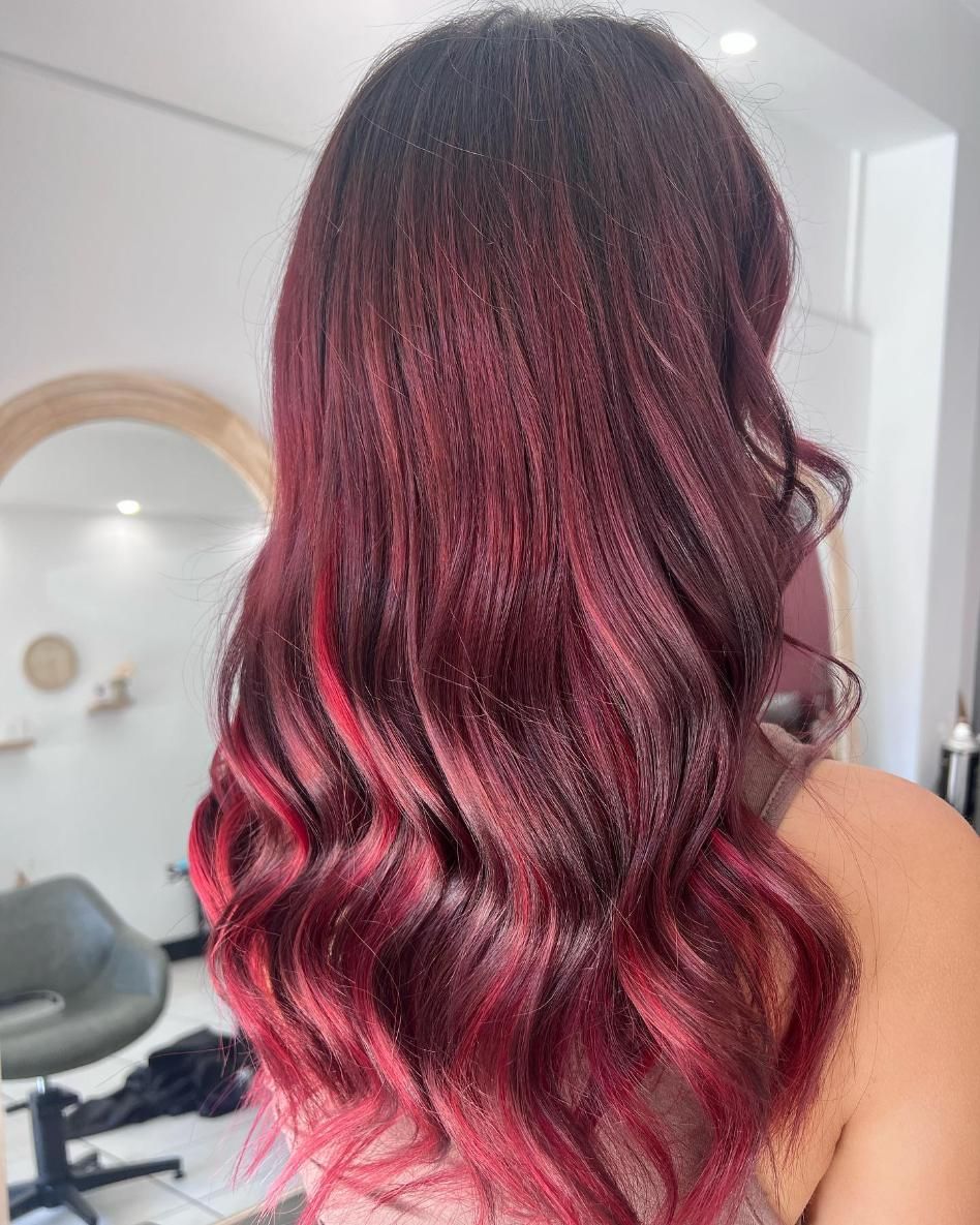 A Woman with Red Hair Is Standing in Front of A Mirror in A Salon — Losh Hair Lounge In Toowoomba City, QLD