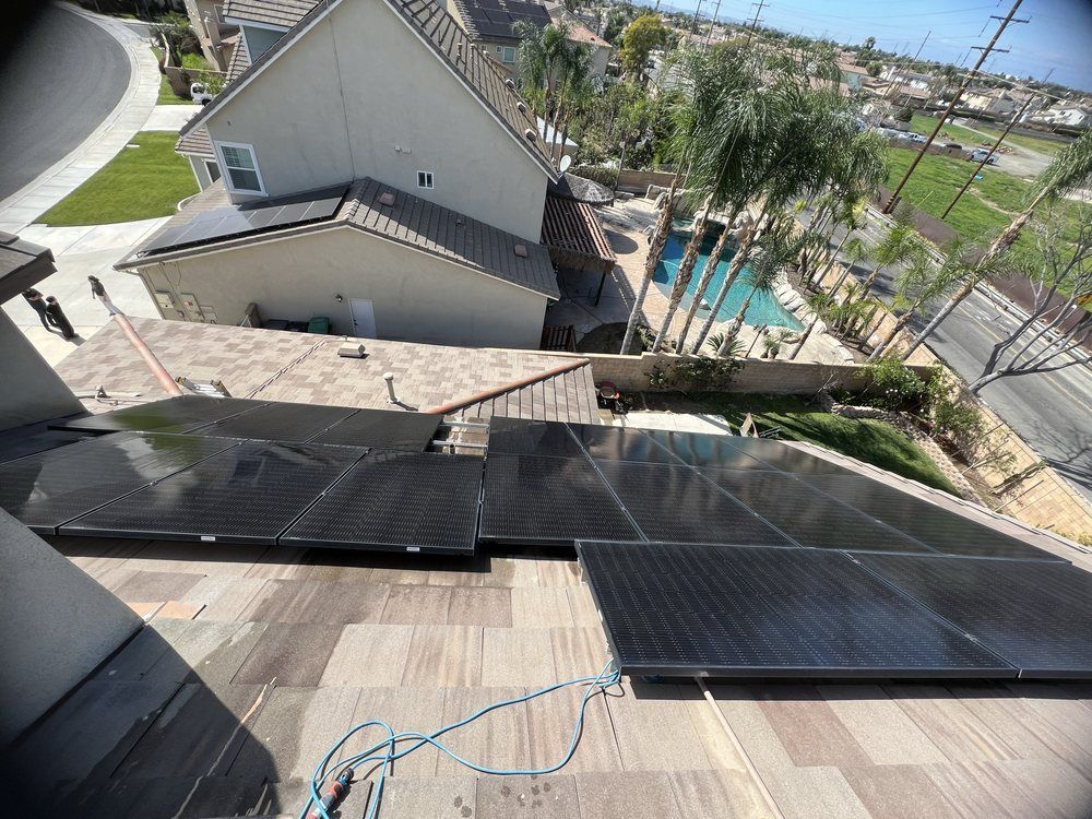 An overhead view of solar panels being installed on a tiled residential roof, with a backyard pool visible below.