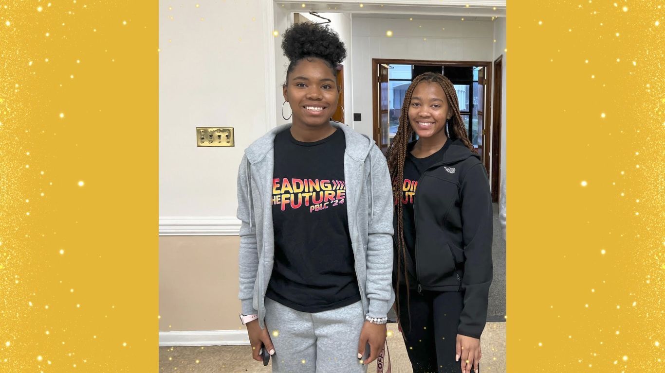 Two young women are standing next to each other in a room.