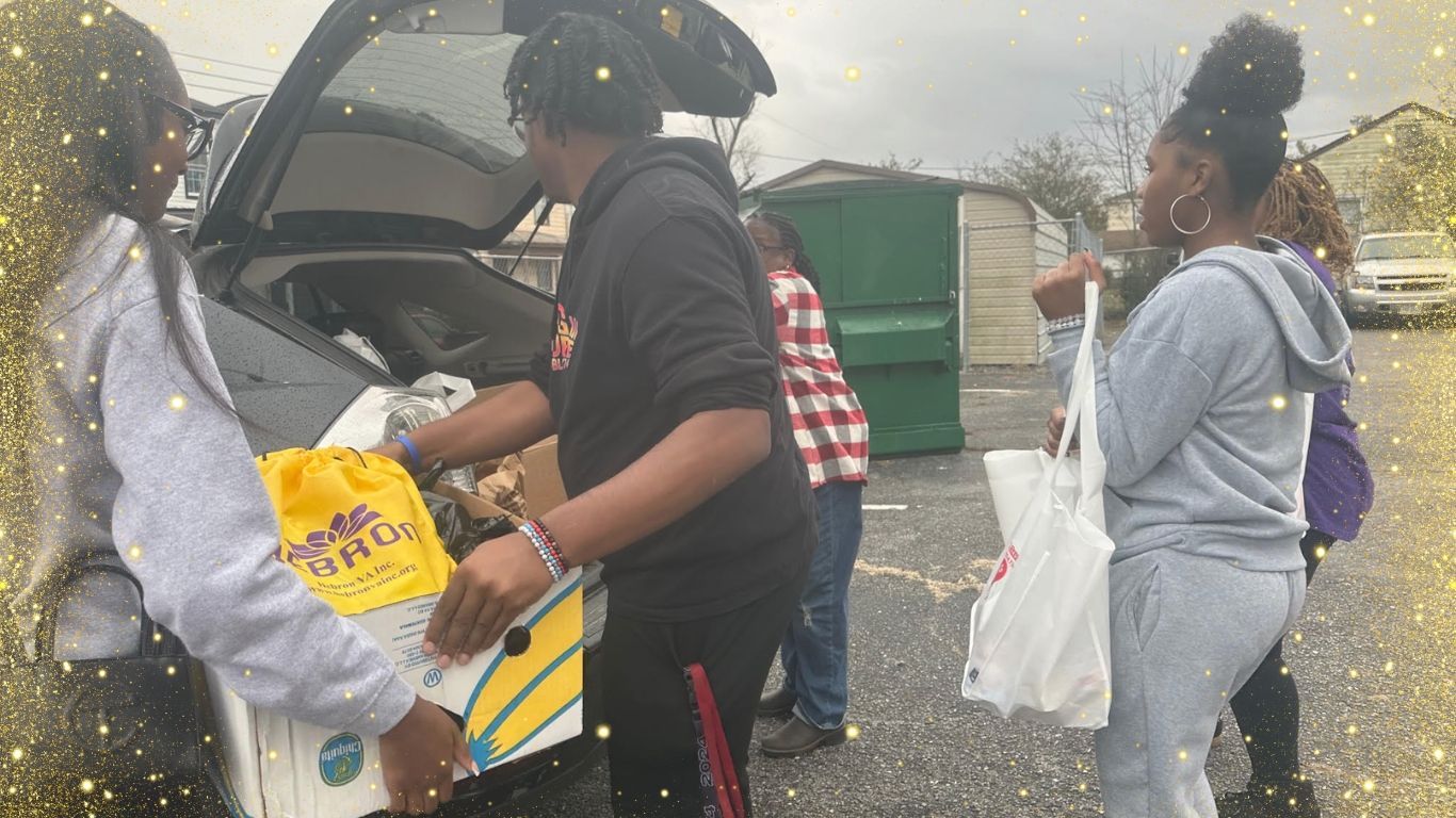 A group of people are loading boxes into the back of a car.