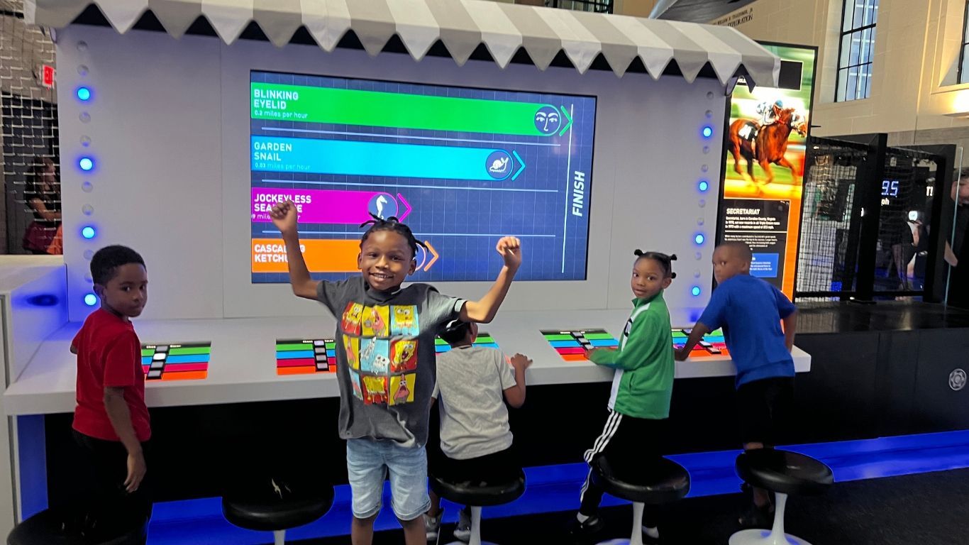 A group of children are playing a video game in front of a large screen.