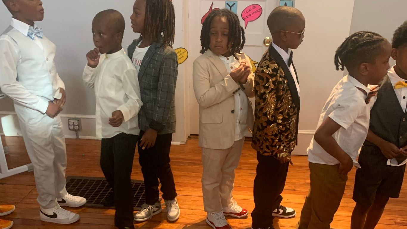 A group of young boys are standing in a line wearing suits and bow ties.