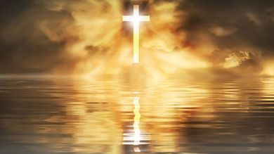 A person is praying with their hands up in front of a cross.