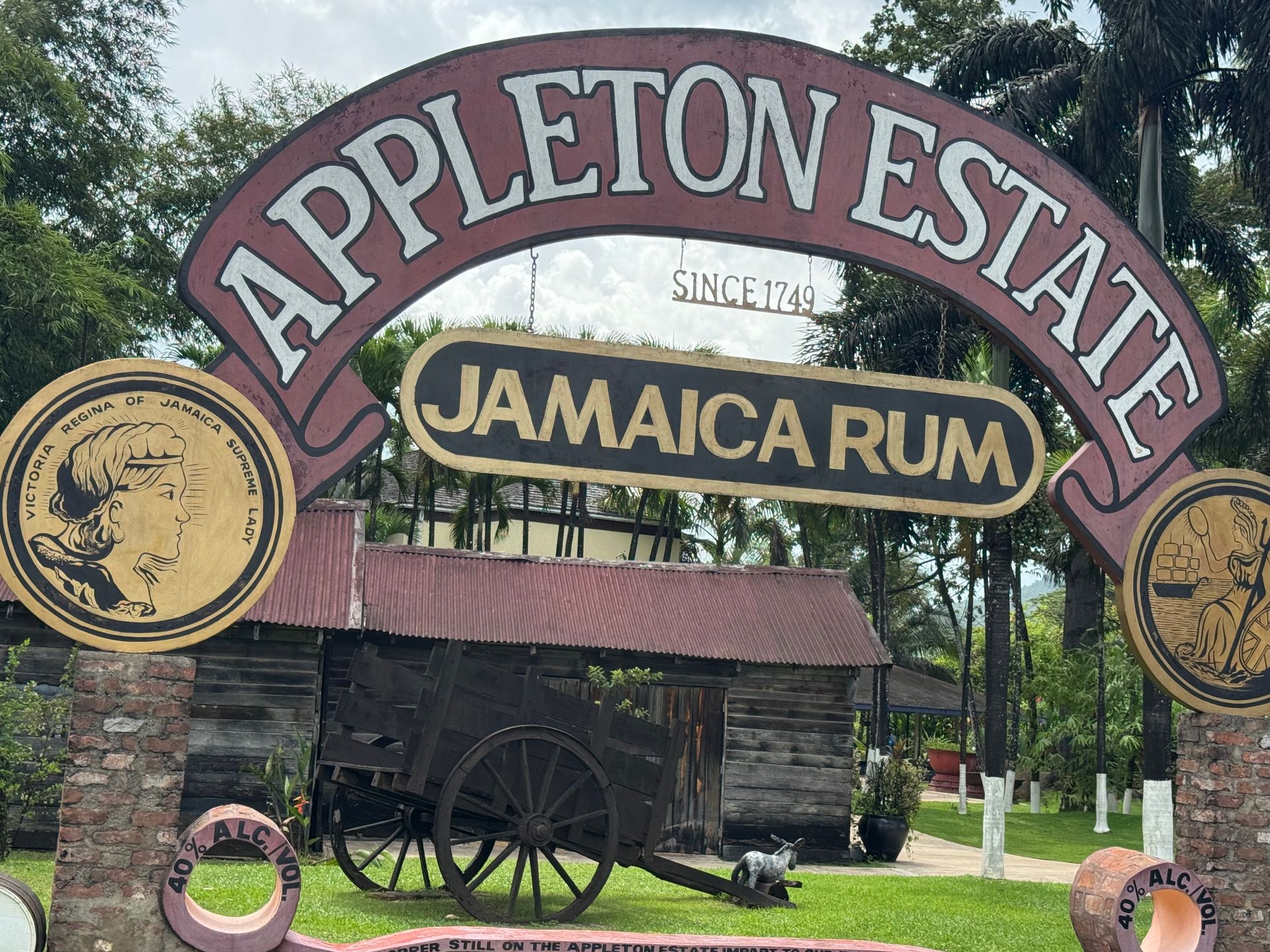 Appleton Estate Jamaica Rum sign, archway entrance, rustic building, and vintage cart.