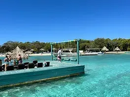 A group of people are standing on a dock in the middle of the ocean.