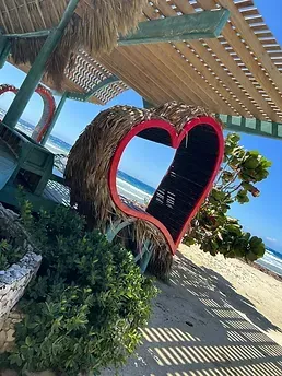 There is a heart shaped chair on the beach.